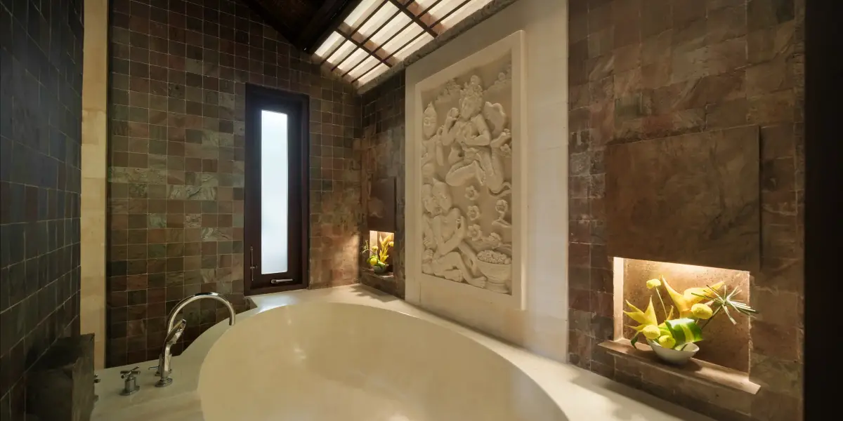 Villa Ambiente — Master bathroom with round bathtub and carved stone panel