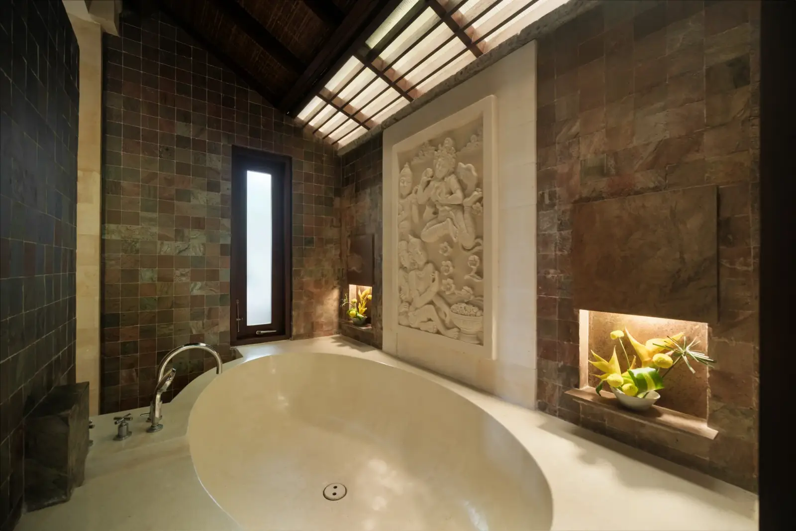 Villa Ambiente — Master bathroom with round bathtub and carved stone panel